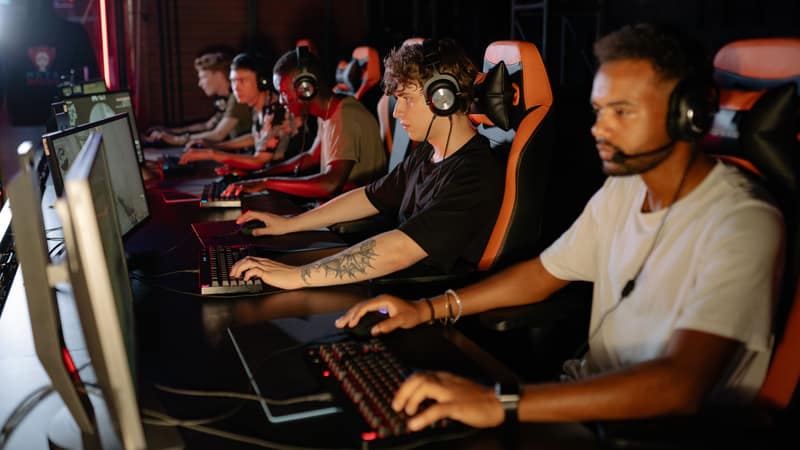 A group of focused young gamers playing in an intense esports tournament indoors.