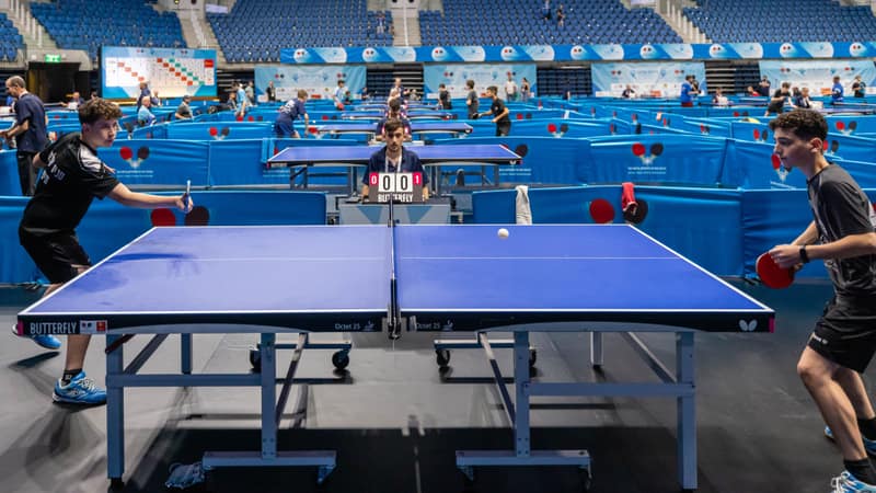 Players compete in a lively table tennis tournament in a large indoor stadium.